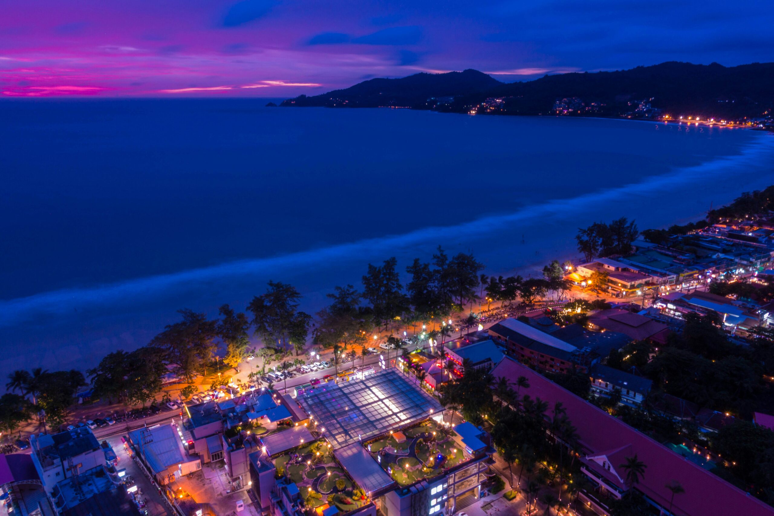 Aerial view of Phuket coastline and beach town lit up at night
